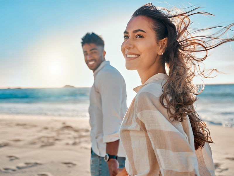 Love, happy and holding hands with couple on beach for honeymoon, relax and travel vacation. Summer, happiness and smile with man and woman walking on date for romance, care and support together.